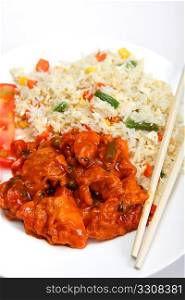 Sweet and sour chicken on a plate with chopsticks, vegetable fried rice and sliced tomato