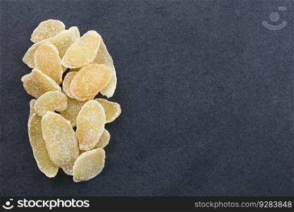 Sweet and spicy candied or crystallized ginger slices photographed overhead on slate with copy space on the side. Candied or Crystallized Ginger Slices
