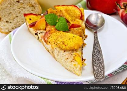 Sweet bread pudding of peaches with milk and eggs, a spoon in a plate on a linen towel, milk in glass jug, cinnamon on a wooden boards background