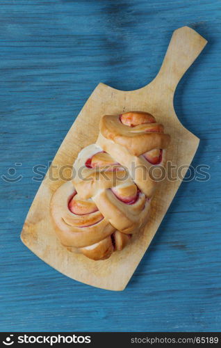 Sweet bun with a cowberry jam on an old cutting board, top view