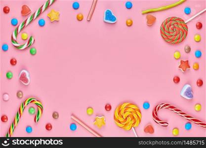 Sweet candy copy space frame with lollipops on pink background. Love to colorful sweetmeats in childhood concept. Sweet candy copy space frame with lollipops on pink background