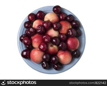 Sweet cherries and ripe juicy nectarines in a dish, on white background. Healthy food with vitamins. Top view.
