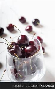 Sweet cherries in cherry  glass bowl around white. close up