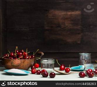 Sweet cherry jam and jelly preserve preparing on rustic wooden background, place for text, kitchen scene
