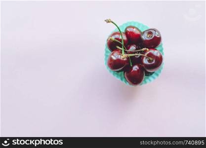 Sweet cherry on a pink background. Ripe sweet cherry in a blue plate close-up. Top view. Free space for text. Sweet cherry on pink background. Ripe sweet cherry close up.