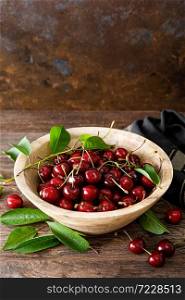 Sweet cherry with leaves in wooden bowl. Fresh ripe cherries. Cherry fruit