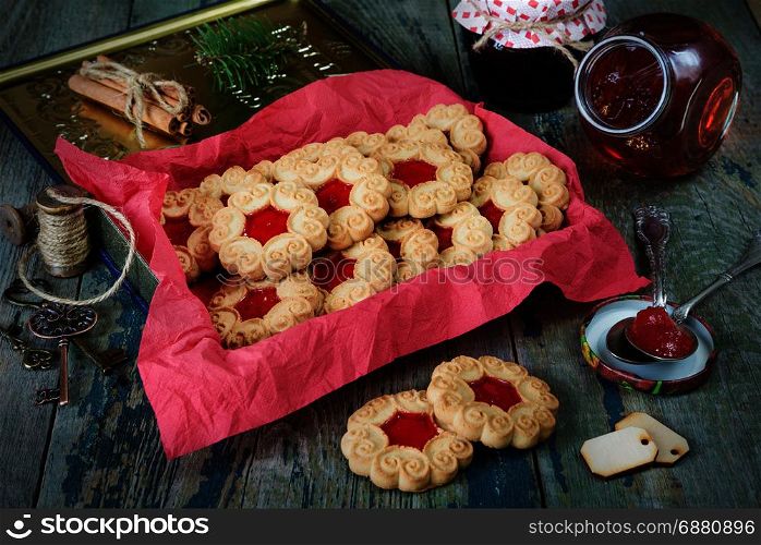 Sweet Christmas cookies with jam and fir branche on the old wooden table