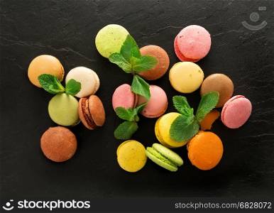 Sweet colorful macarons on black stony table