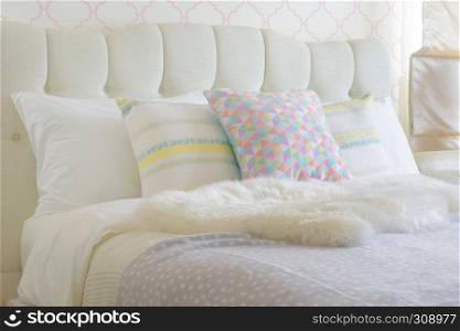 Sweet colorful pillows setting on bed with puffy scarf