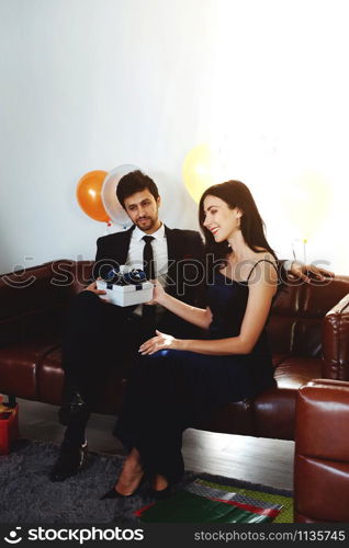 Sweet couple Love smile and spending Romantic christmas time and celebrating new year eve on Brown Sofa decoration with Christmas tree, colorful balloon and Gift Boxes in Living room at home