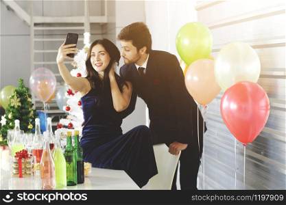 Sweet couple Love smile and spending Romantic for Take a picture with a mobile phone in christmas time and celebrating new year eve, valentine day with colorful balloons in pantry area.