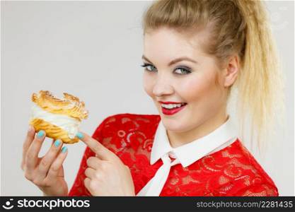 Sweet food and happiness concept. Funny joyful blonde woman holding yummy choux puff cake with whipped cream.. Happy woman holding choux puff cake
