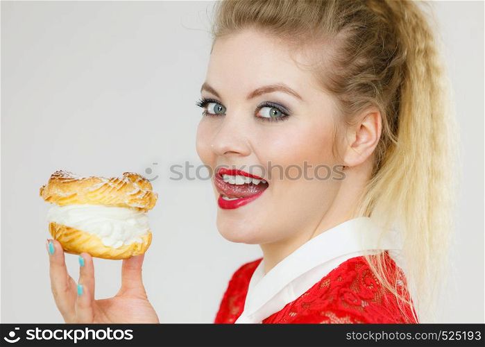 Sweet food and happiness concept. Funny joyful blonde woman holding yummy choux puff cake with whipped cream.. Happy woman holding choux puff cake
