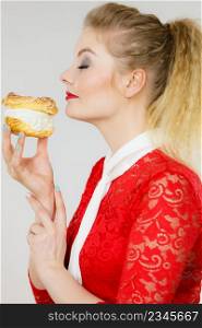 Sweet food and happiness concept. Woman holding yummy choux puff cake with whipped cream.. Happy woman holding choux puff cake
