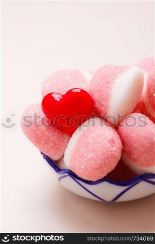 Sweet food candy. Pink jellies or marshmallows with sugar in bowl on wooden table decorated with red heart love symbol