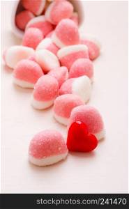 Sweet food candy. Pink jellies or marshmallows with sugar in white bowl on wooden table decorated with red heart love symbol