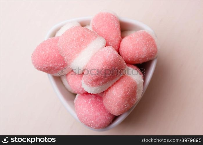 Sweet food candy. Pink jellies or marshmallows with sugar in white bowl on wooden table