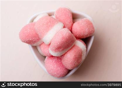 Sweet food candy. Pink jellies or marshmallows with sugar in white bowl on wooden table