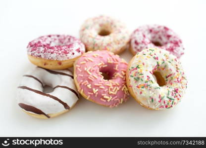 sweet food, junk-food and unhealthy eating concept - close up of glazed donuts on white table. close up of glazed donuts on white table