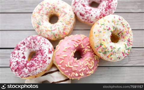 sweet food, junk-food and unhealthy eating concept - close up of glazed donuts over grey boards on background. close up of glazed donuts on grey boards