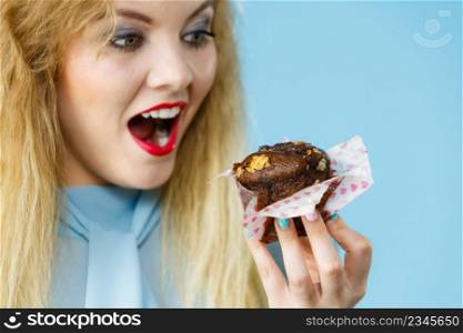 Sweet food sugar make us happy. Attractive blonde woman holds yummy chocolate cupcake in hand, open mouth, craving for cake.. Attractive woman holds cake in hand