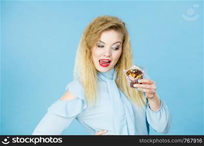 Sweet food sugar make us happy. Attractive blonde woman holds yummy chocolate cupcake in hand, open mouth, craving for cake.. Attractive woman holds cake in hand