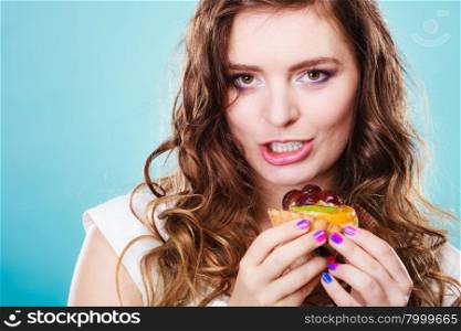 Sweet food sugar make us happy. Cute young woman colorful makeup nails holds fruit cake in hand blue background