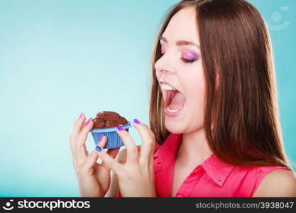 Sweet food sugar make us happy. Smiling woman holds cake chocolate muffin in hand blue background