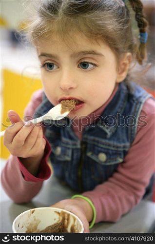 Sweet girl gets dirty eating chocolate ice cream with spoon