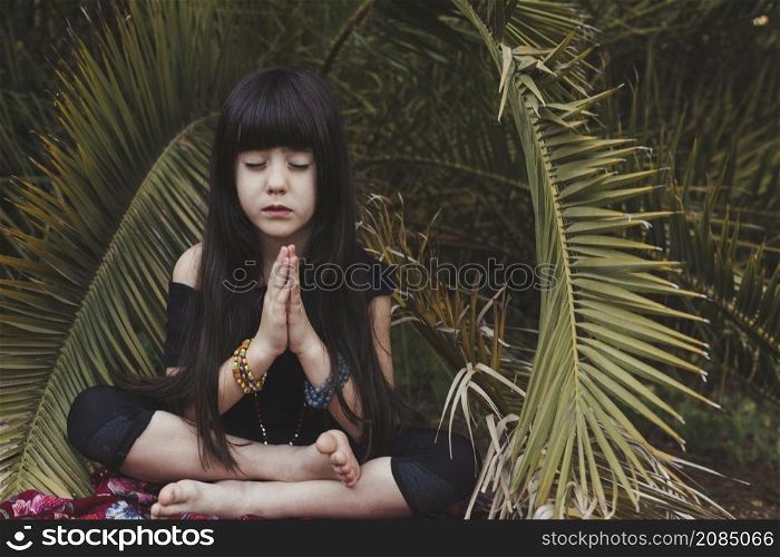 sweet girl meditating near palm