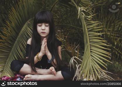 sweet girl meditating near palm