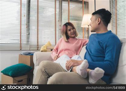 Sweet happy young Asian couple moving clothes and many objects from old home to their new home and relax on sofa in living room at their home. Lifestyle couple move new home.