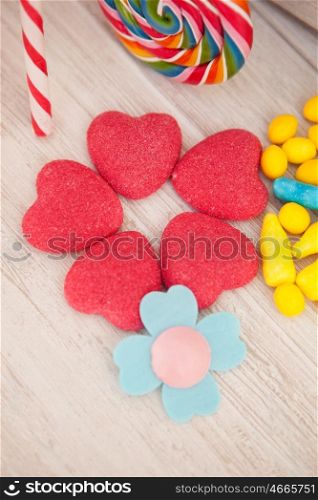 Sweet hearts shaped and other candies on wooden grey background