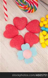 Sweet hearts shaped and other candies on wooden grey background