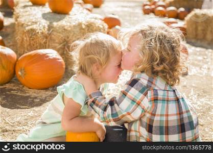 Sweet Little Boy Kisses His Baby Sister in a Rustic Ranch Setting at the Pumpkin Patch.. Sweet Little Boy Kisses His Baby Sister in a Rustic Ranch Setting at the Pumpkin Patch.