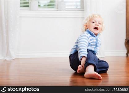 Sweet little boy with mouth open sitting on floor