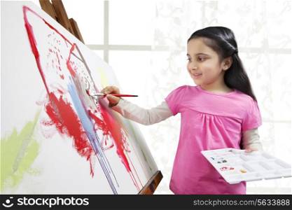 Sweet little girl painting on artist canvas during art class