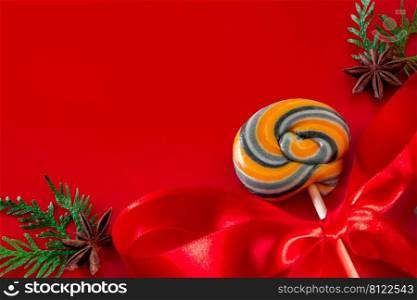 Sweet lollipop and fir twigs with cones. Christmas composition on a red background. Place for text. Sweet lollipop and fir twigs with cones. Christmas composition on a red background.