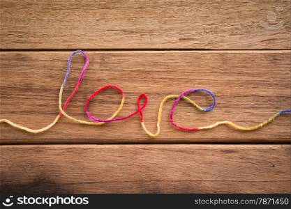 Sweet love word from colorful yarn place on wood texture, wedding and valentine&rsquo;s day symbol