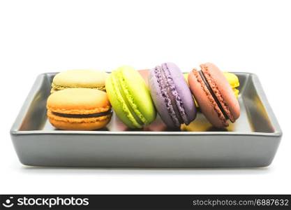 Sweet macarons in a black plate on white background