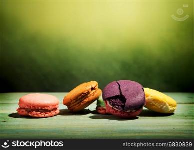 Sweet macarons on a wooden table and green background