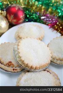 Sweet mince pies with tinsel and christmas balls.