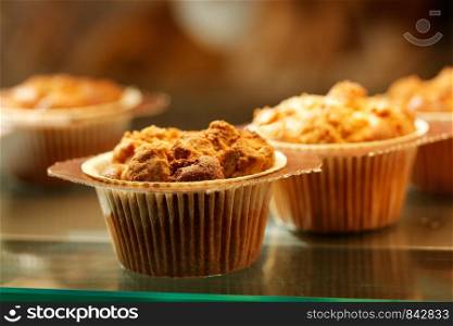 Sweet muffin cupcakes in glass display at the bakery. Selective focus.