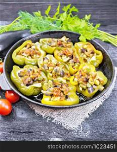 Sweet pepper stuffed with mushrooms, tomatoes, zucchini, eggplant and onions, seasoned with wine, garlic, thyme and spices in a frying pan on sackcloth against wooden board