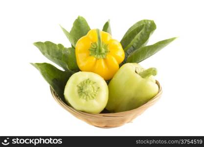 Sweet pepper. Sweet pepper with green leaves in straw Dish. (Clipping work path included)