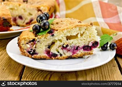 Sweet piece of cake with black currant on a plate, napkin on the background of wooden boards