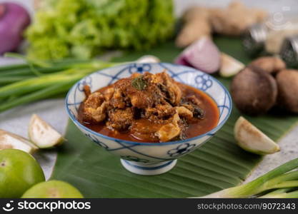 Sweet pork in a ceramic bowl, deer on a banana leaf, with spring onions, mushrooms, and lemon.