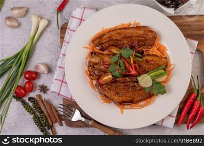 Sweet pork in a white plate with chili, spring onions, carrots, and coriander.