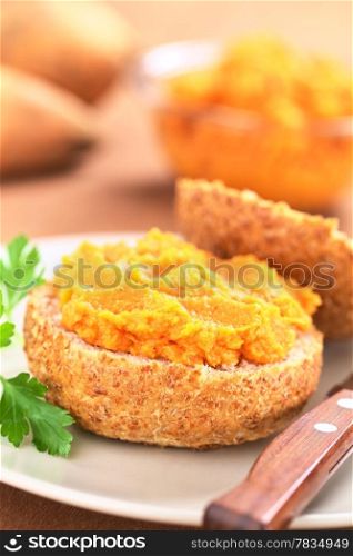 Sweet potato spread on wholegrain bun on plate with knife (Selective Focus, Focus on the front of the spread) . Sweet Potato Spread on Bun