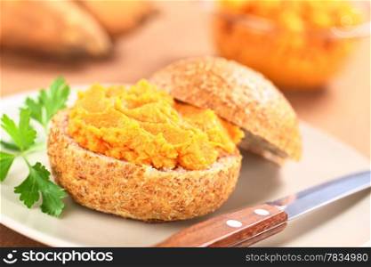 Sweet potato spread on wholegrain bun on plate with knife (Selective Focus, Focus on the front of the spread) . Sweet Potato Spread on Bun